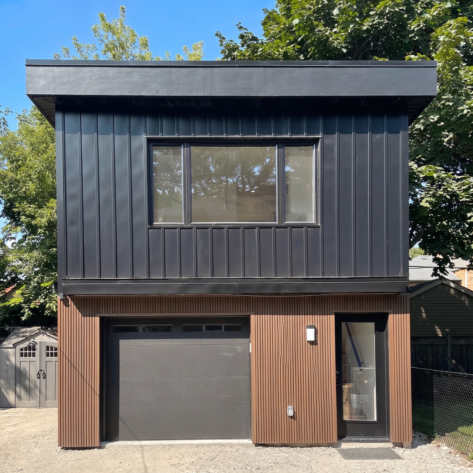 Completed two-storey garden suite with black metal and wood-slat cladding in a Toronto backyard