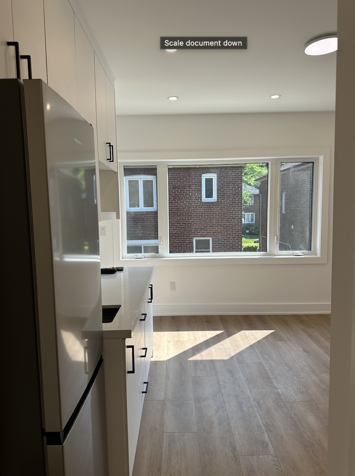 Full kitchen with white cabinetry and stone counters in a two-storey garden suite