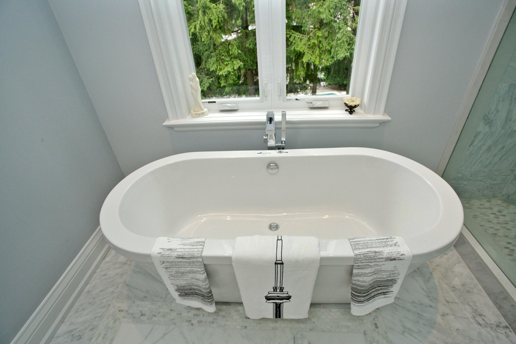 Marble primary ensuite with a freestanding tub in a custom luxury home